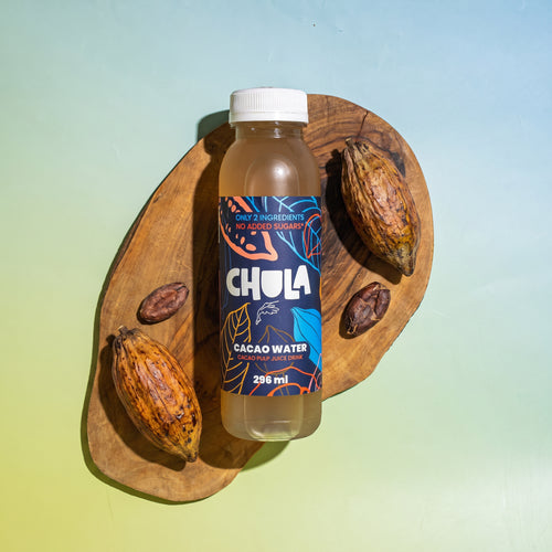 A bottle of CHULA Cacao Water chocolate sauce with a white cap, displayed on a wooden board with cacao pods against a blue-to-green gradient background.